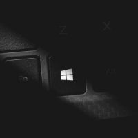 Dramatic black and white close-up of a keyboard's Windows key, featuring stark lighting and shadow.