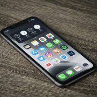 A smartphone with a home screen full of app icons on a wooden surface