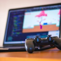 black laptop computer beside controller on brown wooden surface